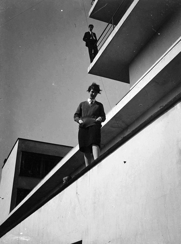 Bauhausgebäude mit zwei auf einem Balkon stehenden Personen*