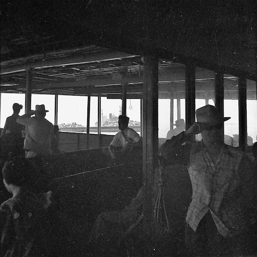 An Bord der Staten Island-Fähre. Passagiere unter Deck und Schrott-Prahm im Hintergrund