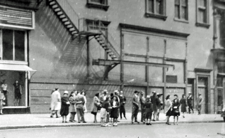 Street Scene. People waiting at the Curb, Fire Escape on the Building Wall