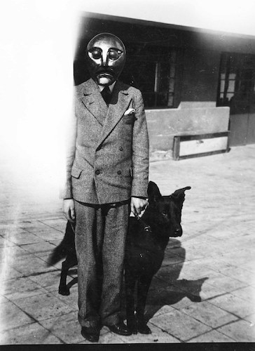 Mann mit Maske im Straßenanzug, Hund bei Fuß
