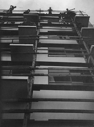 Blick nach oben, Ateliergebäude mit Anstreichergerüst und Menschen