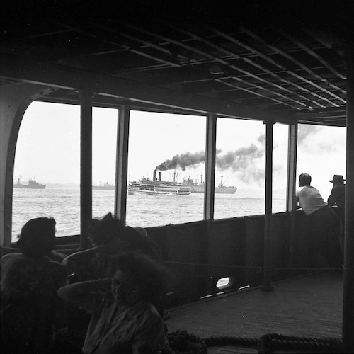 An Bord der Staten Island-Fähre. Blick auf Ausflugsdampfer und aufliegende Victory Ships