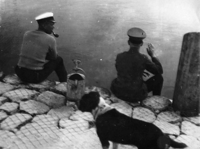 Zwei Männer und ein Hund am Rega-Ufer