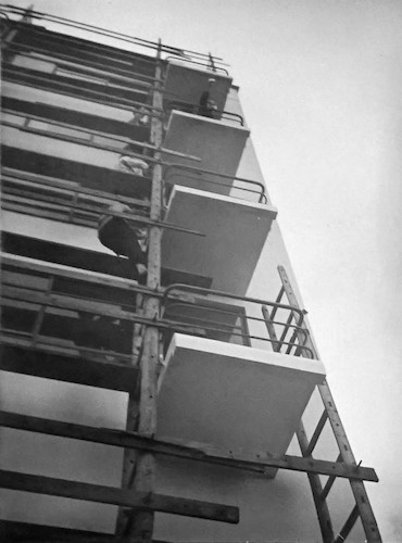 Blick nach oben, Nordostwand des Ateliergebäudes mit Anstreichergerüst. Drei Menschen klettern hoch