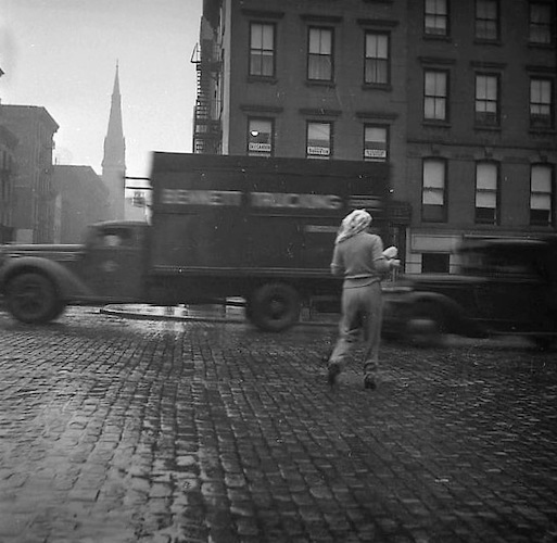 Rainy Day. Woman crossing a cobblestone Street, 