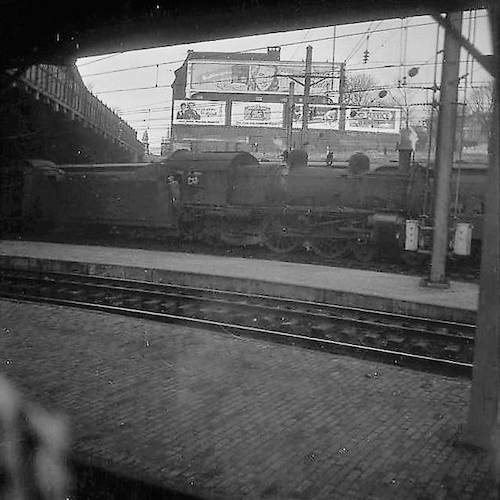 View from a Train on Platforms, an Engine and Billboard