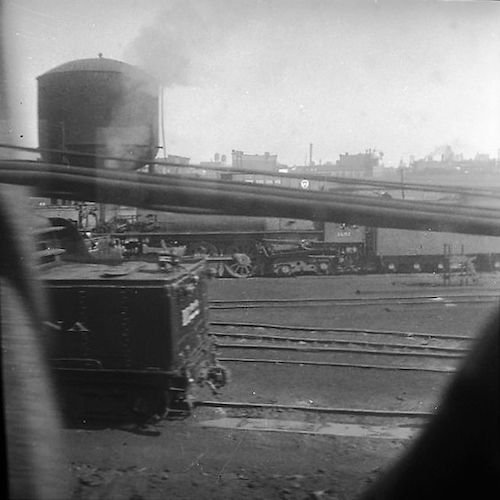 Blick aus einem Zug auf Industrieanlage und Gleise