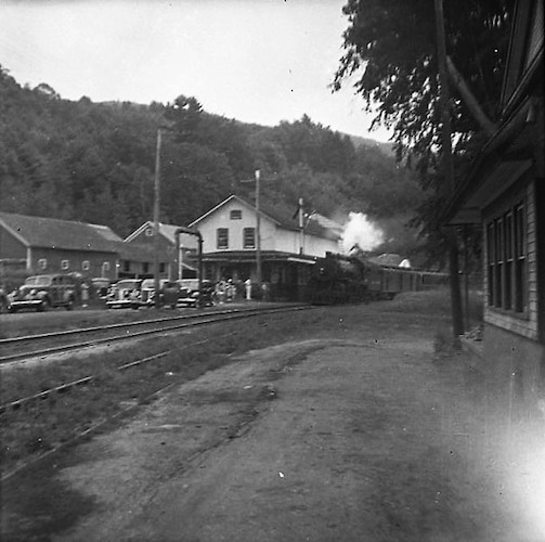 Train station in the Countryside with Train arriving and parked Cars